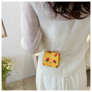 Détail d'un mini sac à bandoulière jaune à motif fraises avec chaîne dorée
