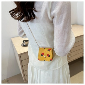 Gros plan d'un mini sac jaune à imprimé fraises avec bandoulière chaîne sur un mannequin