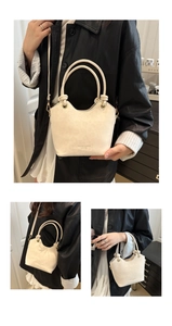 Detail of cream-white leather bucket bag with thick rope knot handle and gold hardware