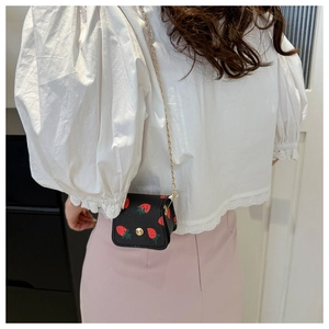 Détail du mini sac à chaîne avec imprimé fraise et boucle en métal doré porté