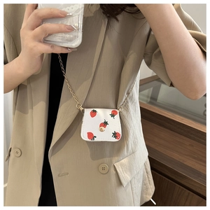 Vue détaillée du mini sac fraise blanc avec bandoulière chaîne dorée sur l'épaule