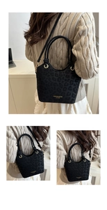 Detail of black leopard print bucket bag with gold lettering and woven handle strap