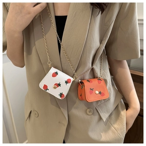 Détail de mini sacs fraise en blanc et orange avec bandoulière en chaîne dorée chic