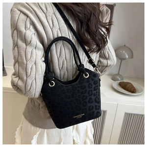 Detail of black leopard print bucket bag with gold hardware and logo on leather