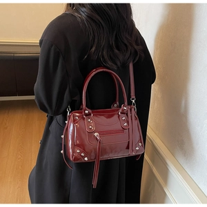 Dettaglio della borsa Boston in vernice bordeaux con borchie argento e nappine lunghe