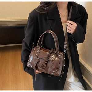 Détail du sac Boston marron brillant avec clous argentés et glands en cuir