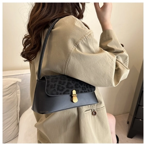 Close-up of black shoulder bag featuring leopard print flap and vintage gold lock