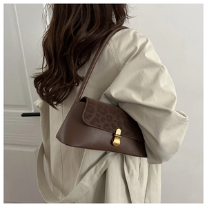 Detail of leopard print flap and gold metal clasp on a dark brown leather underarm bag