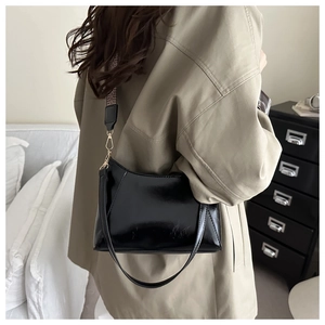 Détail du sac oreiller en cuir verni noir avec bandoulière jacquard et sangle en cuir