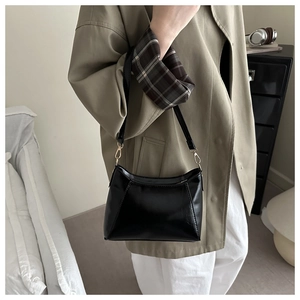 Détail du sac sous le bras en cuir verni noir avec boucle en métal doré chic