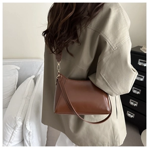 Sac bandoulière en cuir marron avec large sangle porté par un mannequin