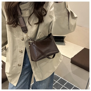 Détail du sac demi-lune marron foncé avec bandoulière large tissée et cuir fin