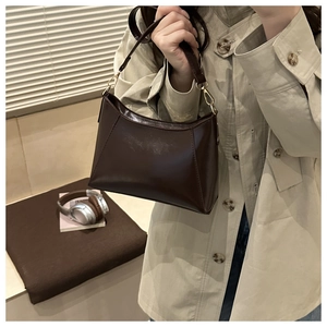 Détail du sac oreiller en cuir marron foncé avec bandoulière et crochets en métal doré