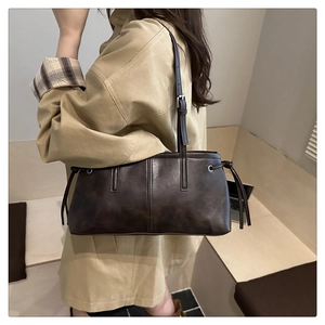 Detail of dark brown vintage faux leather shoulder bag with side drawstring accents
