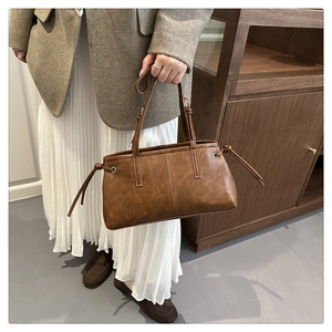 Detail of the brown leather tote bag showing drawstring closure and dual handle design