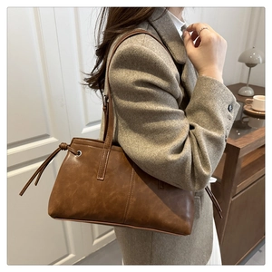 Close-up of brown PU leather shoulder bag with wax texture and side knot details