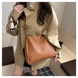 Caramel brown PU leather bucket bag with stylish knotted strap detail on woman model