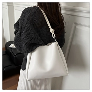 Detail of white leather tote bag with handcrafted knotted shoulder strap for daily commuting