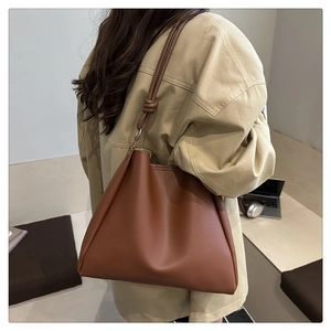 Detail of soft dark brown PU leather tote bag with elegant knotted shoulder strap design