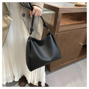 Detail of black vintage bucket bag with knot shoulder strap and matte faux leather texture