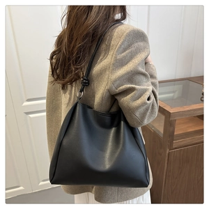 Close-up of minimalist black matte tote bag with knotted strap detail on female model