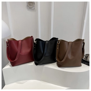 Three minimalist large capacity tote bags in burgundy, black and brown leather on display