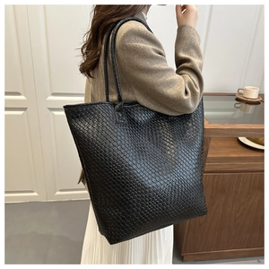 Detail of black woven tote bag showing large capacity and stylish underarm shoulder strap