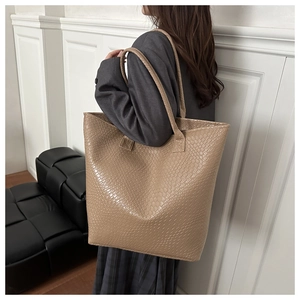 Close-up of a large beige tote bag featuring textured woven faux leather and dual handles