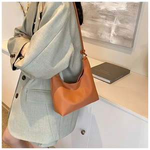 Close-up of orange-brown litchi pattern leather shoulder bag with silver hardware detail