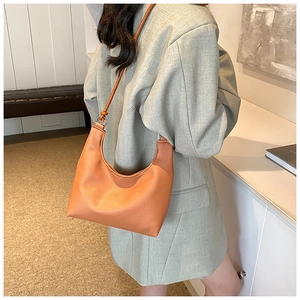 Detail of caramel lychee grain leather crescent bag with smooth shoulder strap texture