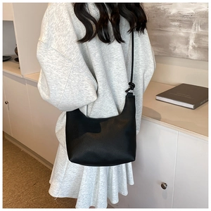 Close-up of black leather moon bag with litchi texture on a modern home background