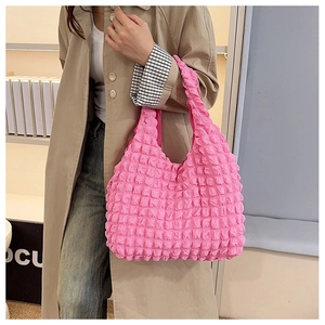 Detailed view of pink bubble textured shoulder bag worn by model in minimalist studio