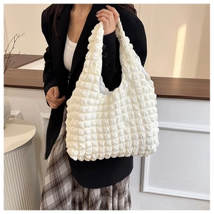 Detail shot of the white popcorn textured fabric and seamless shoulder strap on the bag