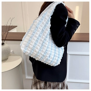 Side view of model wearing a light blue popcorn fabric pleated hobo bag