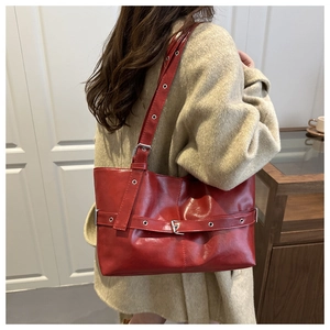 Close-up of red glossy PU leather tote bag with stylish belt buckle and metal eyelets