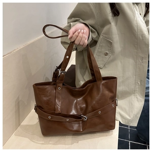 Detailed shot of dark brown PU leather tote bag with decorative strap and metal buckle