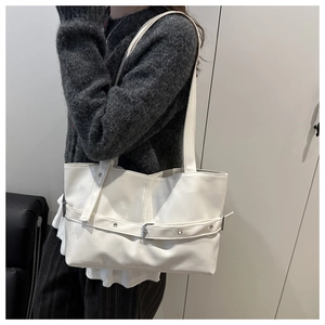 Detail of minimalist cream faux leather tote bag with silver buckle and slim shoulder straps
