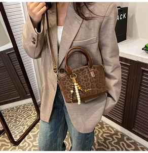 Close-up of leopard print handbag with suede texture, wooden bead tassel and leather strap