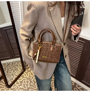 Dettaglio borsa a tracolla leopardata marrone con nappa di perline su blazer beige