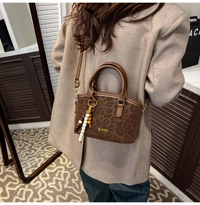 Brown leopard print handbag featuring beaded fringe tassel and adjustable shoulder strap
