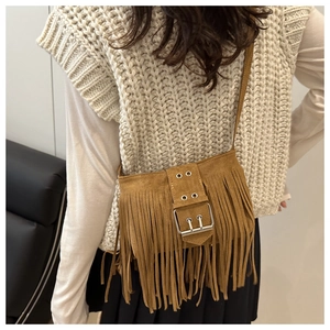 Close-up of retro brown suede crossbody bag featuring long fringes and metal buckle detail