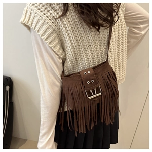 Close-up of brown suede tassel crossbody bag featuring a large vintage metal buckle detail