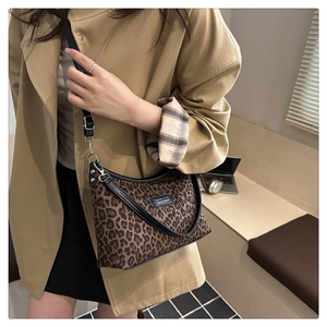 Detail of leopard print crossbody bag with black leather trim and adjustable strap