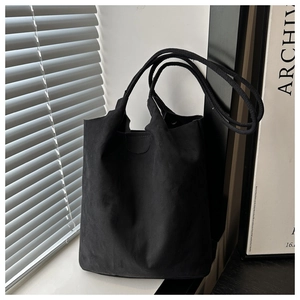 Minimalist black canvas tote bag with side lighting highlighting soft texture and drape