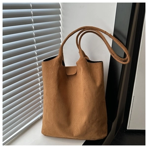 Detail of soft brown suede tote bag with dual handles and minimalist stitching texture