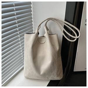 Detail of minimalist off-white frosted bucket bag with long shoulder straps and magnetic closure