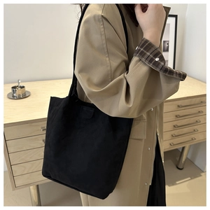 Detail of minimalist black suede shoulder bag paired with a classic khaki trench coat
