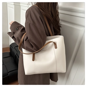 Detail of minimalist cream leather tote bag with brown handles and fashion text