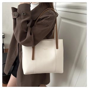 Detail of minimalist white tote bag with brown straps and gold fashion logo engraving