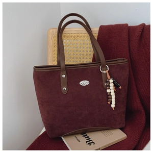Détail du sac cabas en daim bordeaux avec brides en cuir et breloque en perles rustique